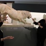 Two people next to a statue of a lion