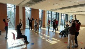 People stretching in a large room with windows
