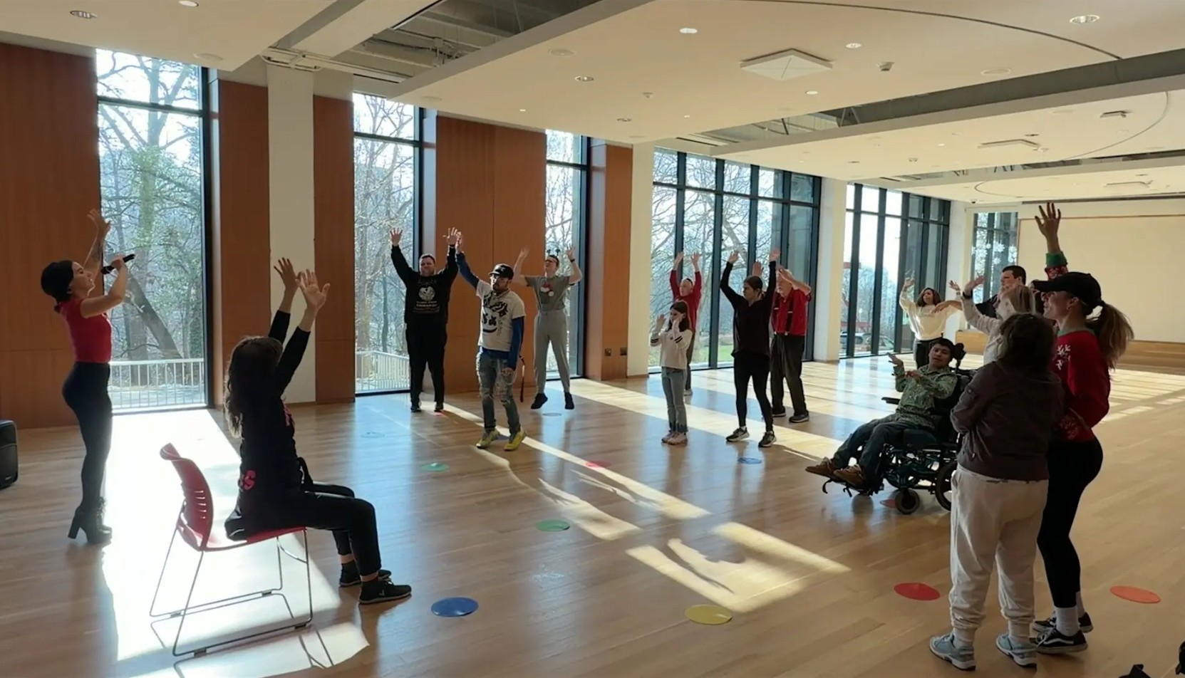People stretching in a large room with windows